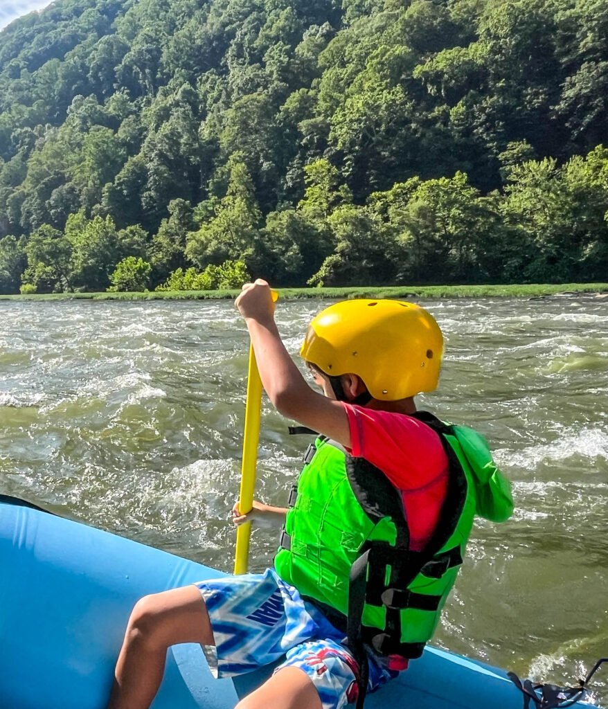 Kid padding a raft over rapids