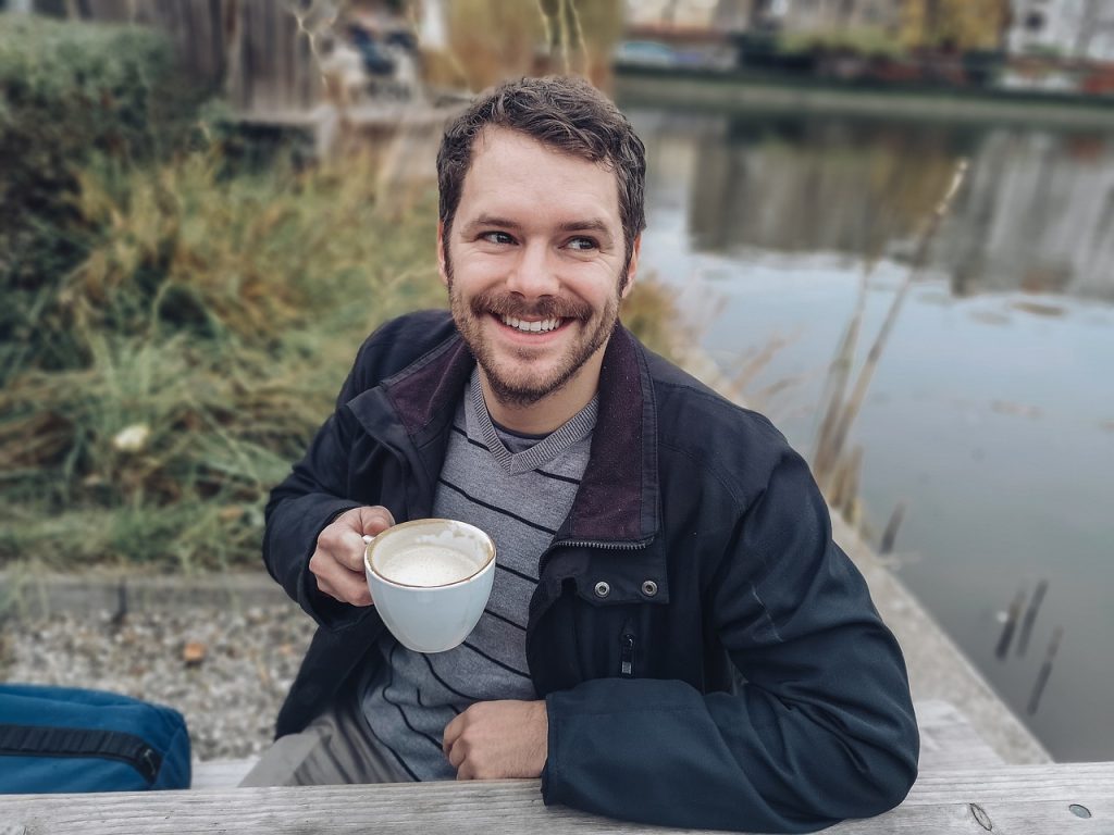Man by river drinking coffee