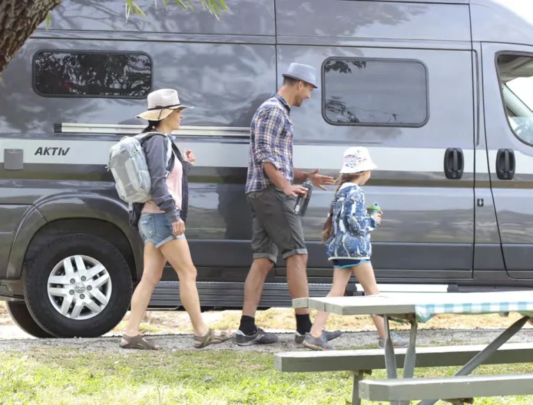 Family walking past a Hymer Aktiv parked at a campsite picnic table